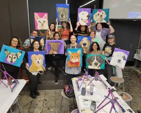 Staff team picture holding up paintings of dogs